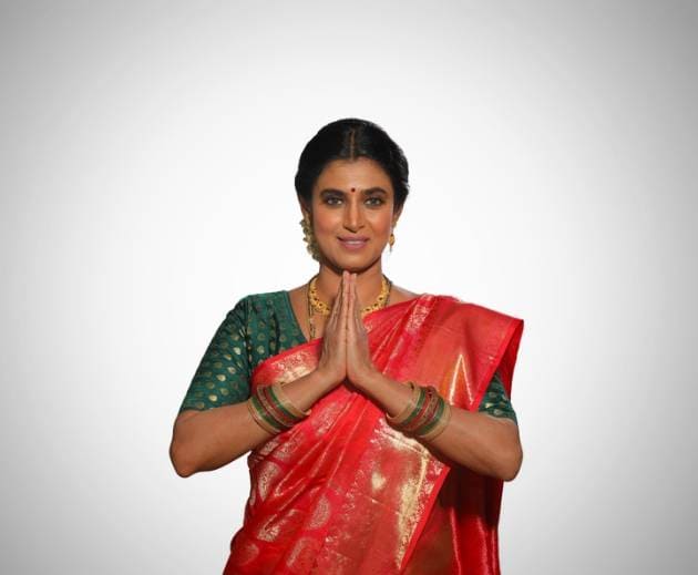 A woman in a red sari gracefully gesturing, adding elegance and cultural significance to her attire.
