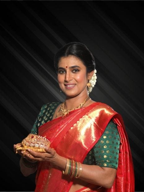An indian woman in a red sari holding a gold plate.